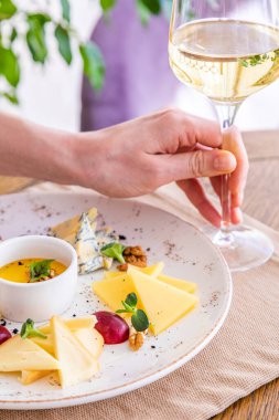 El bir bardak beyaz şarap alır. Peynir tabağı. Çeşitli peynirlerle dolu bir tabak. Atıştırmalıklar Peynirli bir bardak şarap..