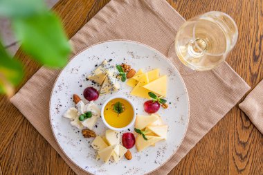 Peynir tabağı. Çeşitli peynirlerle dolu bir tabak. Atıştırmalıklar Peynirli bir bardak şarap..