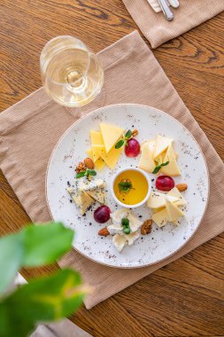 Peynir tabağı. Çeşitli peynirlerle dolu bir tabak. Atıştırmalıklar Peynirli bir bardak şarap..