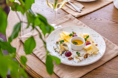 Peynir tabağı. Çeşitli peynirlerle dolu bir tabak. Atıştırmalıklar Peynirli bir bardak şarap..