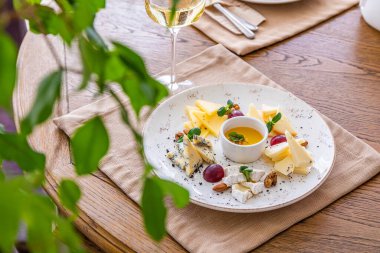 Peynir tabağı. Çeşitli peynirlerle dolu bir tabak. Atıştırmalıklar Peynirli bir bardak şarap..