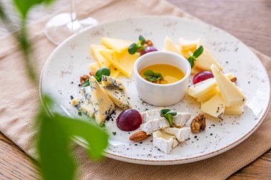 Peynir tabağı. Çeşitli peynirlerle dolu bir tabak. Atıştırmalıklar Peynirli bir bardak şarap..