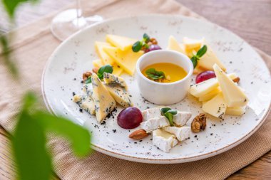 Peynir tabağı. Çeşitli peynirlerle dolu bir tabak. Atıştırmalıklar Peynirli bir bardak şarap..