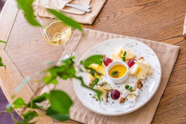 Peynir tabağı. Çeşitli peynirlerle dolu bir tabak. Atıştırmalıklar Peynirli bir bardak şarap..