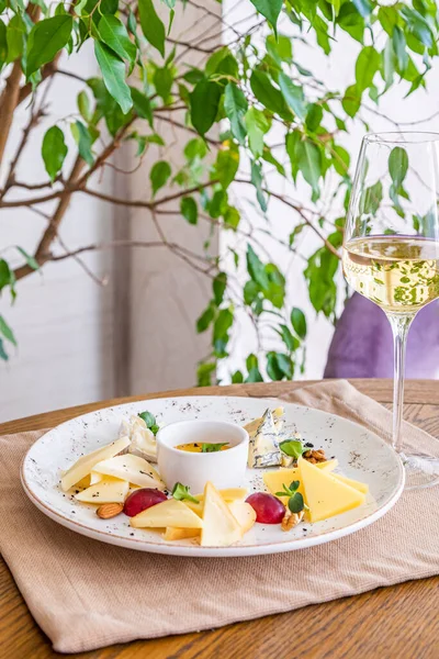 Peynir tabağı. Çeşitli peynirlerle dolu bir tabak. Atıştırmalıklar Peynirli bir bardak şarap..