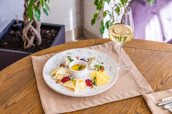 Peynir tabağı. Çeşitli peynirlerle dolu bir tabak. Atıştırmalıklar Peynirli bir bardak şarap..