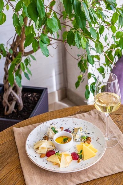 Peynir tabağı. Çeşitli peynirlerle dolu bir tabak. Atıştırmalıklar Peynirli bir bardak şarap..