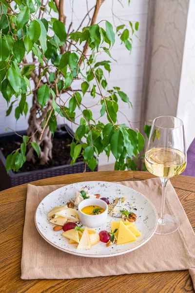 Peynir tabağı. Çeşitli peynirlerle dolu bir tabak. Atıştırmalıklar Peynirli bir bardak şarap..