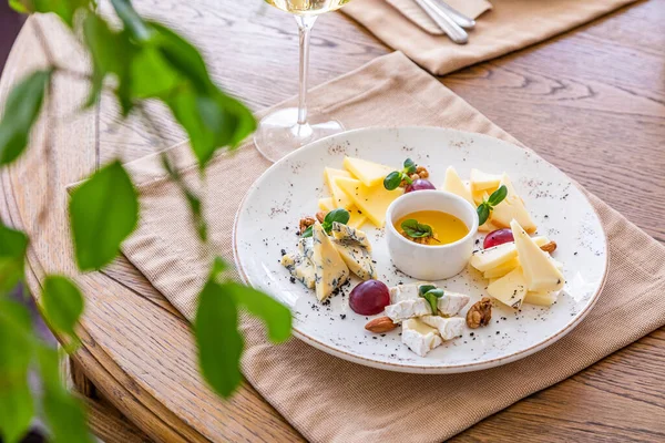 Peynir tabağı. Çeşitli peynirlerle dolu bir tabak. Atıştırmalıklar Peynirli bir bardak şarap..