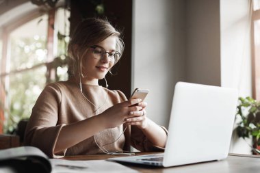 Eğitim ve sevinçle müzik dinleme dizüstü bilgisayar, kulaklık, giyen üzerinden proje hazırlama smartphone tutarak ve gelecek tarih ile ilgisini iletideki answear okuma kadın mola