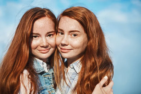 They make puzzle complete together. Good-looking happy female with red hair and freckles, hugging and smiling, gazing happily at camera, being in close relationship, trusting and loving each other