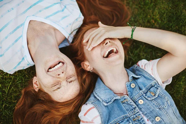 Dostluk bir mucizedir. Çiller, yeşil çim üzerinde yalan ve yüksek sesle, gülerek, dalga geçmeyi ve having fun gözleri kapsayan kadın gülüyor neşeli ve kaygısız şirin kızıl saçlı kızlarla