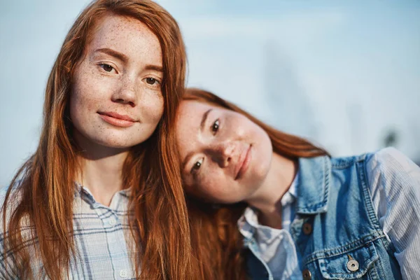 Ő mindig is az ő oldalán. Bájos, gondtalan nővére-szeplős és a vörös hajú, mosolyogva és érzés öröm, asszony támaszkodva barátom váll, míg a tengerpart közelében ült, és élvezi gyönyörű naplemente — Stock Fotó