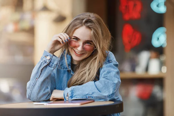 Ingin membeli saya minum. Charming genit dan sensual european pacar dengan rambut pirang, melihat dari bawah dahi dengan menarik dan mengisyaratkan ekspresi, melepas kacamata hitam, menatap kamera — Stok Foto