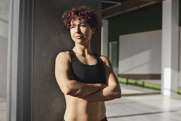 운동복 입고 스포츠 브래지어 교차점에 결정된 스포티 한 젊은 sportswoman 손 체육관에서 창 밖에 서 찾고, 생산적인 운동 훈련, 에어로빅 강사 대기 클래스 후 휴식 — 스톡 사진