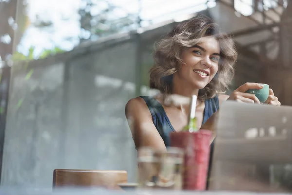 Erfolgreiche selbstbewusste junge Studentin digitale Nomadin sitzen Fenster Bar Café Blick außerhalb Kamera halten Tasse trinken Kaffee lächelnd erfreut beenden wichtige Projekt erfüllen Frist, Arbeit Laptop — Stockfoto