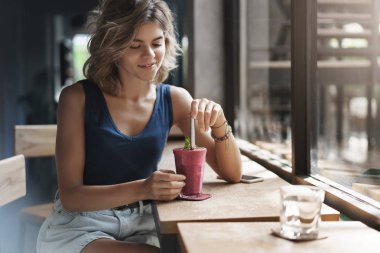 İhale büyüleyici genç modern kentsel kadın sarışın kısa saç modeli pencere bar sehpa karıştırma smoothie saman bakmak içki şehvetli güzel öğle yemeği molası bekleyin telefon görüşmesi keyfini çıkarın