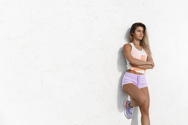 Determinado motivado apuesto joven deportista caucásico apoyándose en los brazos cruzados de la pared del muelle de concreto sobre el pecho confiado, parpadeando mirando el amanecer, entrenamiento matutino listo, descansando después del yoga — Foto de Stock