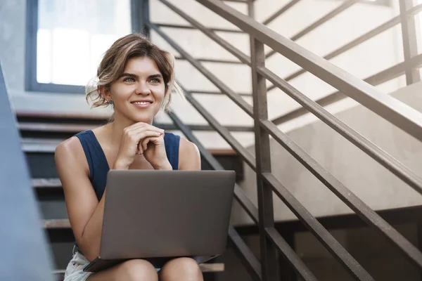 Charmante jonge dromerige vrouwelijke student zitten buiten Universiteit Campus trappen afwerking project glimlachend blij kijken opzij houden laptop knieën freelance taak indienen, nieuw programma werken — Stockfoto