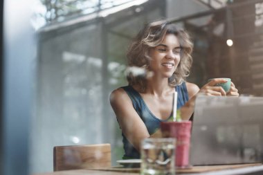 Çekici başarılı modern genç iş kadını SMM Yöneticisi yeni online yazı Cafe Bar içecek kahve bakmak memnun dizüstü ekran, Freelance çalışma, ilginç makale okuma oturup tanıtmak oluşturmak