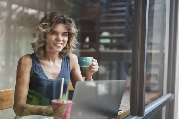 Berhasil menarik perhatian wanita pirang Eropa pendek gaya rambut keriting terus cangkir kopi kerja laptop foto lepas, duduk bar kafe jendela melihat di luar inspirasi pencarian — Stok Foto