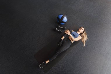 Yüksek açı görünümü motive sporstwoman aktif giyim spor lastik paspas üzerinde uzanan, yoğun crossfit egzersizleri önce bacaklar ısınma germe, med-ball ve halter ile eğitim oturumu