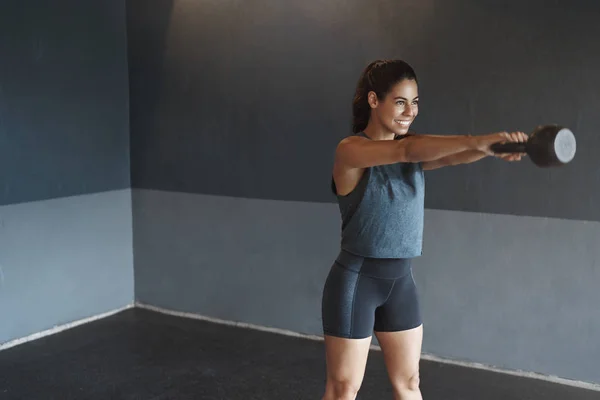 Motivation, strengths and sport concept. Determined strong attractive hispanic sweaty woman workout alone gym, wear activewear, lift kettlebell during crossfit squats, smiling pleased gain muscles