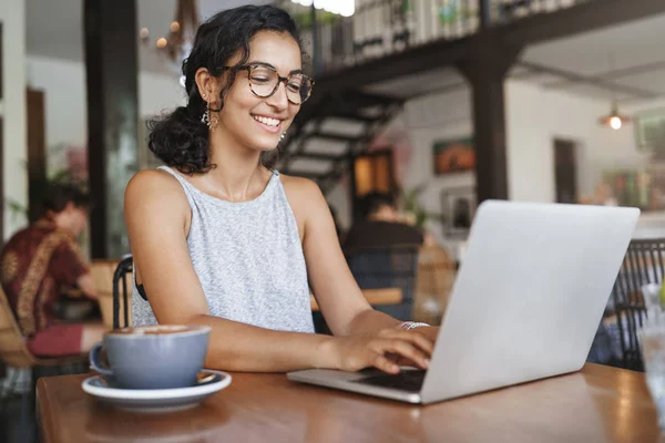 Freelance, business e e-commerce concetto. Giornalista femminile entusiasta creativa che scrive nuovo articolo, digitando sul computer portatile, sorridendo, annotando le idee di progetto, si sieda il caffè, beva il caffè che lavora remoto — Foto Stock