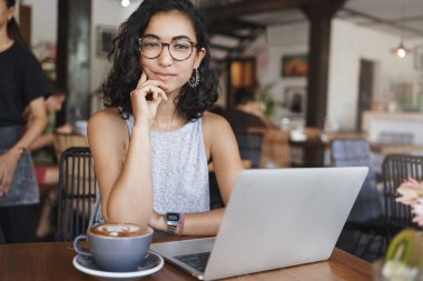 Serbest, e-öğrenme ve iş konsepti. Çekici şık hipster kız, kız öğrenci üniversite projesi hazırlamak tek başına sehpa, co-çalışma alanı, içki kapuçino, dizüstü bilgisayar ile çalışma