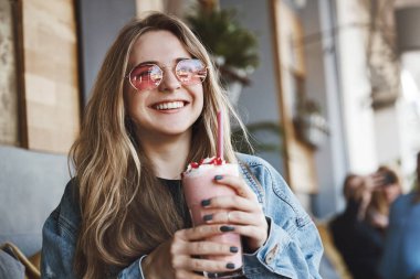 Yakışıklı adam numara sormaya geldiğinde kızlar gelişigüzel konuşuyor. Güneş gözlüğü büyüleyici kaygısız ve şık kadın Portresi, çilek kokteyl tutan ve bir kenara geniş bir gülümseme ile bakan