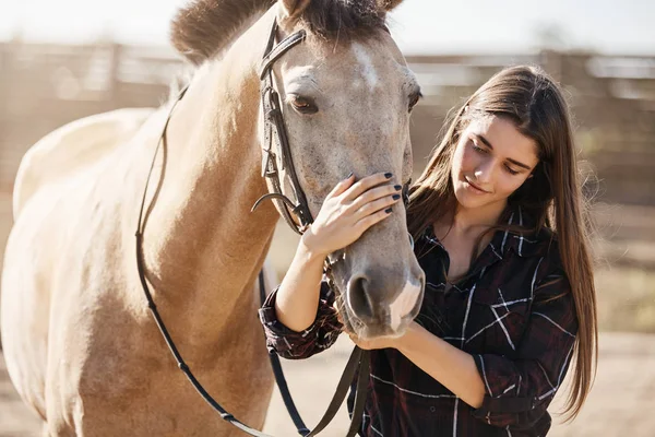 Zvířata, přátelství a hobby koncept. Krásná mladá žena na venkově se usmívá, jemně okřejí koňský nos, veterinář pečuje o domácí mazlíčky na venkovském statku, učí děti být žertem — Stock fotografie