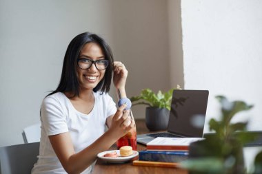 Zaman gıda ile beyin şarj etmek ve daha verimli çalışmaya başlamak. Kafede okuyan gözlüklü kız, tatlı makarna sıcağa ve gülümseyen kameraya tutunan, dizüstü bilgisayardan ev ödevi yiyip okuyan, not alan