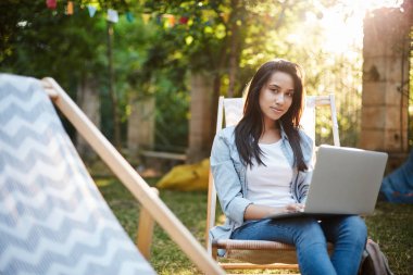 E-öğrenme, genç yaşam tarzı ve doğa kavramı. Çekici kadın girişimci açık havada çalışma malzemesi hazırlamak, parkta piknik sandalyede oturup freelancing olarak dizüstü bilgisayar gülümseyen kamera tutun, uzak bir görev var