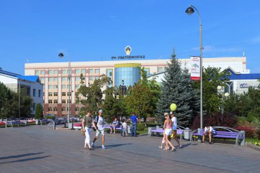 Tyumen, Rusya Federasyonu-Ağustos 14, 2018: Tsvetnoy Bulvarı'nda petrol çıkarma Şirket Llc Rn-Uvatneftegaz binanın arka planı yürümek bir geri kalan vatandaşların sahip