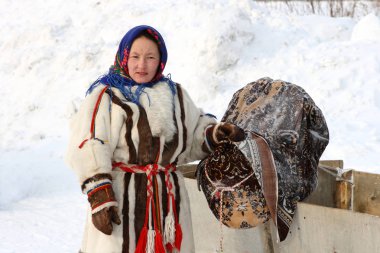 NADYM, RUSSIA - MARCH 07, 2010: Nenets women in winter with a child in the cradle. Nenets - aboriginals of the Russian North clipart