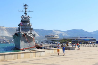 Novorossiysk, Rusya Federasyonu-Ağustos 10, 2015: sahil eski Sovyet Kruvazör Mikhail Kutuzov arka plan üzerinde yürüyen turist