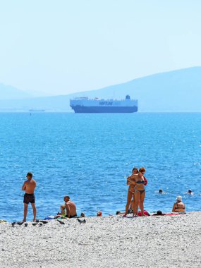 Novorossiysk, Rusya Federasyonu-Ağustos 10, 2015: tatilcilerin sıcak bir günde geminin arka planda Karadeniz kıyısında