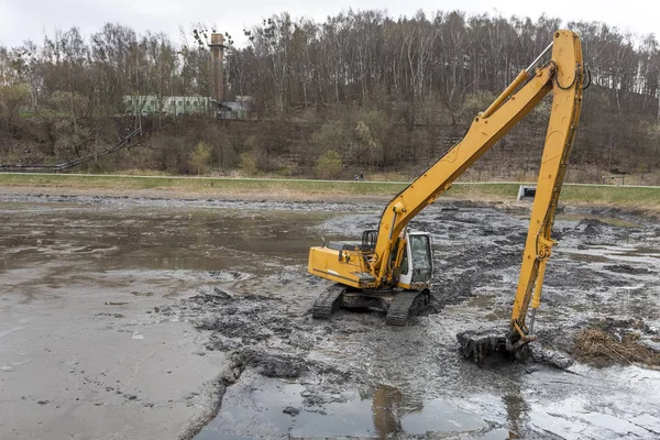 Yellow excavator while working in the mud — Stock Photo, Image