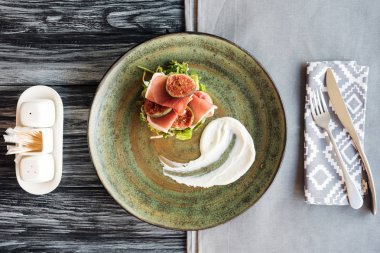 gurme prosciutto üstten görünüm tabak ve çatal bıçak üzerinde ahşap masa ile 