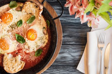 ahşap masa üzerinde lezzetli kızarmış yumurta, çatal bıçak ve çiçeklerle Üstten Görünüm