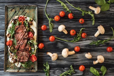 top view of delicious sliced cooked steak with vegetables on wooden table   clipart