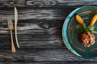 tabak, çatal ve bıçak ahşap masa üzerinde gurme et sosu ve fesleğen yaprakları  