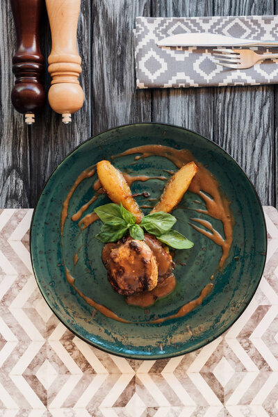 top view of gourmet cooked ribeye beef steak with basil leaves on plate