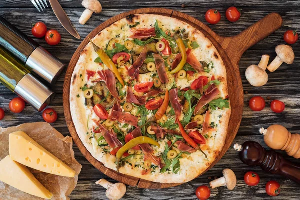 Top view of baked delicious pizza with vegetables, cheese and meat on wooden chopping board — Stock Image Top View Baked Delicious Pizza Vegetables Cheese Meat Wooden Chopping Stock Picture