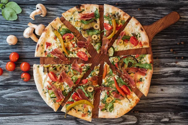 Top view of sliced delicious pizza with vegetables and meat on wooden cutting board — Stock Image Top View Sliced Delicious Pizza Vegetables Meat Wooden Cutting Board Stock Picture