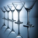 Row of elegant empty martini glasses on grey with reflections