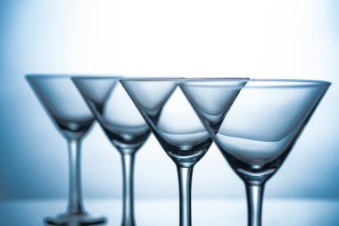 still life with row of empty martini glasses on grey clipart