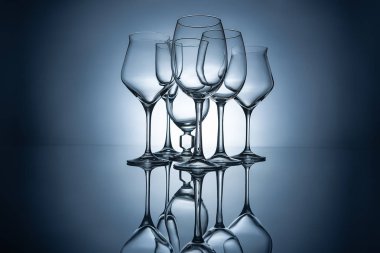 silhouettes of different empty wine glasses with reflections, on grey clipart