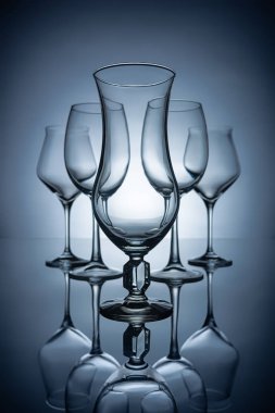 silhouettes of different empty wine glasses with reflections, on grey clipart
