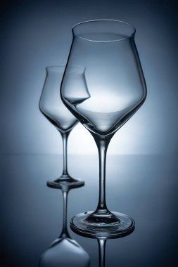 two empty transparent wine glasses on grey with reflections clipart